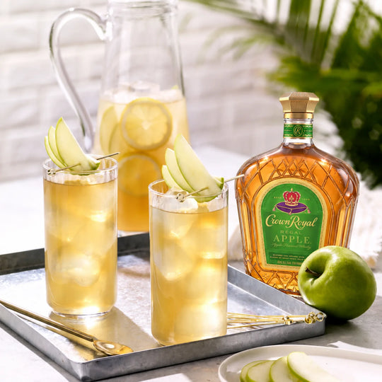 Bottle of Crown Royal Apple with a couple Crown Royal Apple Cocktails