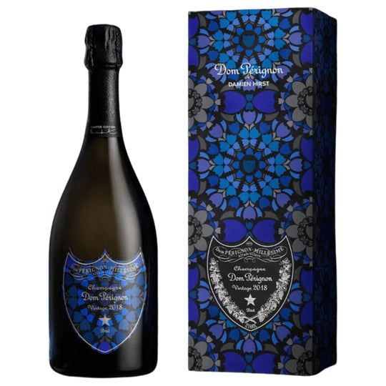 A bottle of Dom Pérignon Vintage 2018 Champagne next to its decorative blue and black patterned gift box designed by Damien Hirst