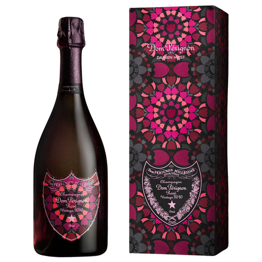 A bottle of Dom Perignon Brut Rose next to its matching decorative packaging box designed by Damien Hirst, both featuring a vibrant magenta and pink floral mandala pattern. 